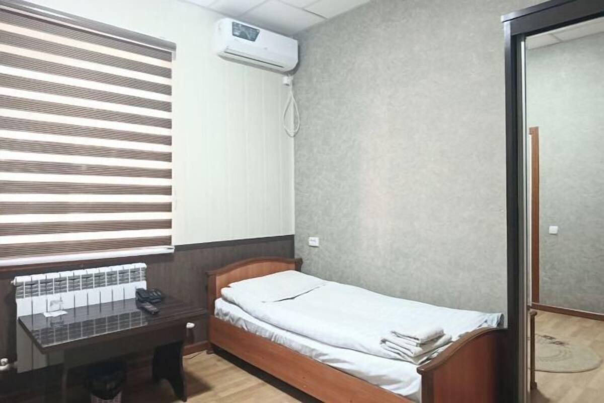 Una habitación con cama, escritorio y ventana con persianas.