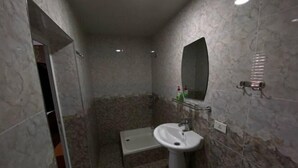 A bathroom with a pedestal sink, a mirror, and a shower area. - N&J Hotel-Process equipment only (Jizzakh District)