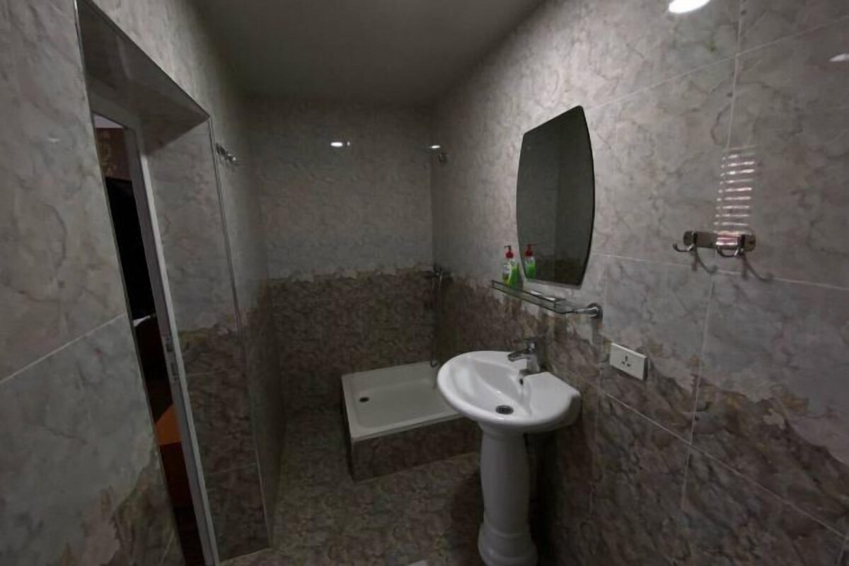 A bathroom with a pedestal sink, a mirror, and a shower area.