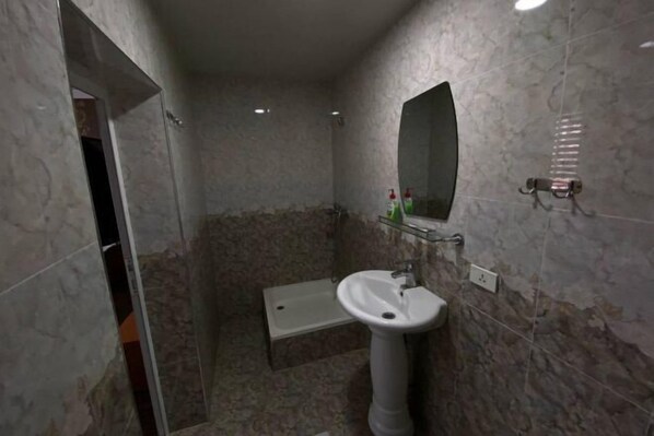 A bathroom with a pedestal sink, a mirror, and a shower area. - N&J Hotel-Process equipment only (Jizzakh District)