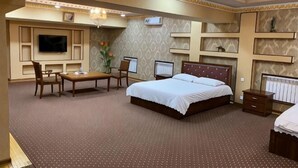 A hotel room with a bed, desk, chairs, TV, and a decorative wall. - N&J Hotel-Process equipment only (Jizzakh District)