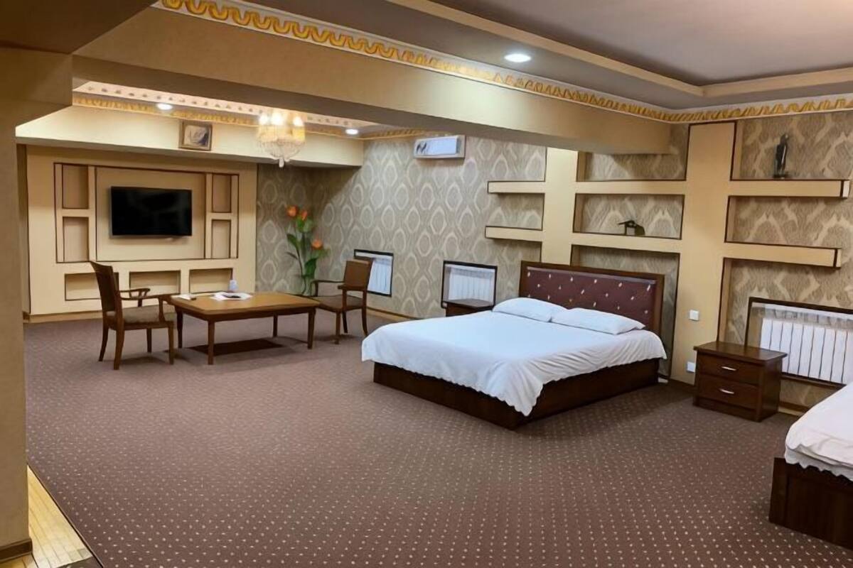 Habitación de hotel con cama, escritorio, sillas, televisor y decoración en la pared.