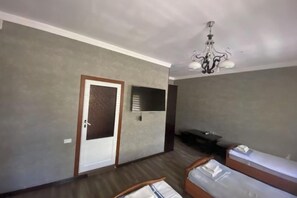 A room with a bed, a door, a television, and a chandelier. - N&J Hotel-Process equipment only (Jizzakh District)