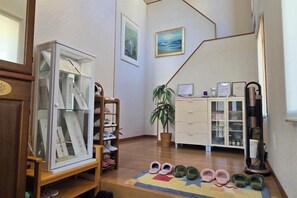 A room with a shoe rack, a plant, a desk with a computer, and a painting on the wall. - Kumano Ayukawa-juku (Tanabe)