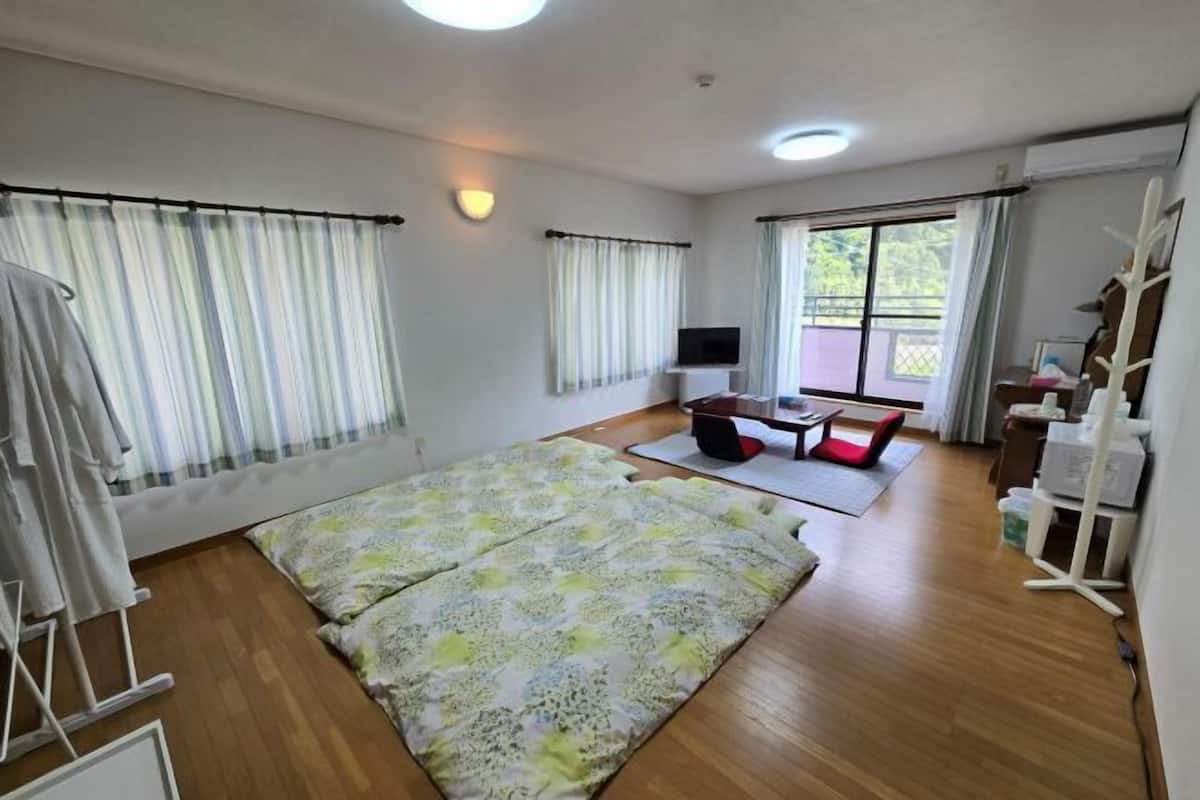 Ein Zimmer mit einem großen Bett, einem Fernseher, einem kleinen Tisch und einem Sessel.