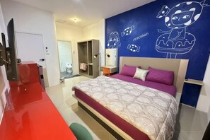 Un dormitorio moderno con una cama grande, una alfombra roja, una pared azul con personajes de dibujos animados y un armario.
