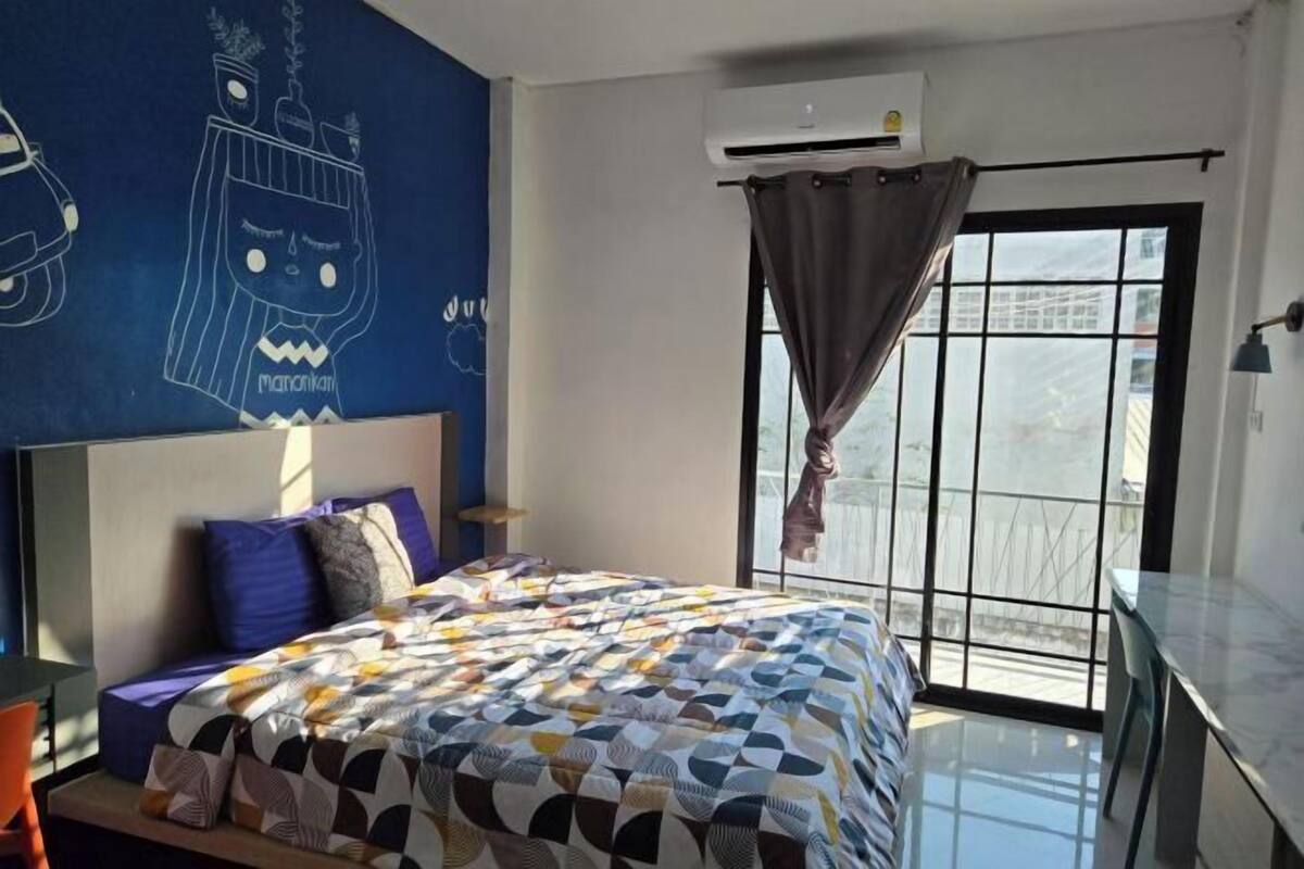 Une chambre avec un grand lit, un mur d’accent bleu, une fenêtre avec vue et un appareil de climatisation.