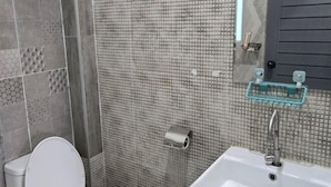 A bathroom with a toilet, a sink, and a shower area. - Manonkan Kranuan (Kranuan)