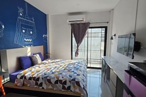 Un dormitorio moderno con una cama, un escritorio, un televisor y un ventanal grande.