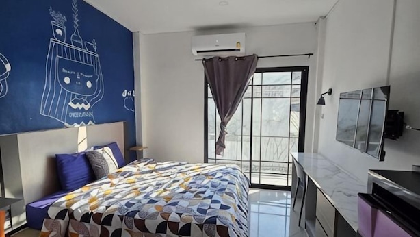 A modern bedroom with a bed, a TV, and a window with curtains. - Manonkan Kranuan (Kranuan)