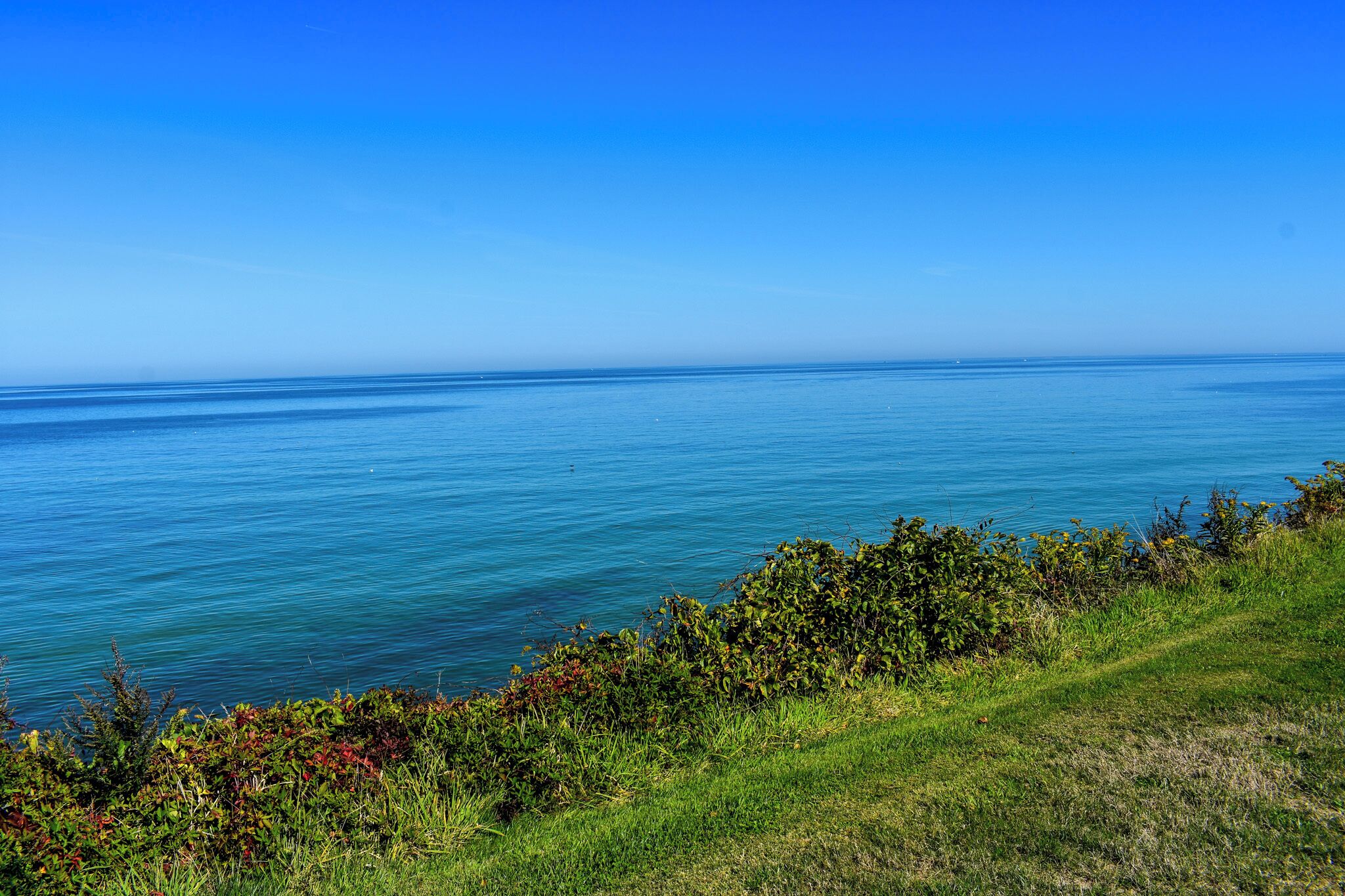 A coastal landscape with a clear view of the sea and grassy terrain.