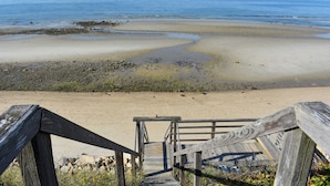 Una escalera de madera que conduce a una playa con vistas claras al océano.