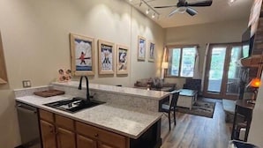 Una cocina moderna con una isla central, armarios de madera y una alfombra roja.