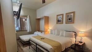Un dormitorio con dos camas, ventilador de techo y un amplio ventanal.