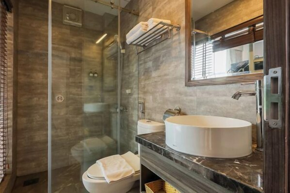A modern bathroom with a glass-enclosed shower, a white sink, and a large mirror.