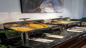 A buffet setup with multiple serving trays, a marble countertop, and a wall-mounted artwork. - 3T Hotel Hanoi (Hanoi)