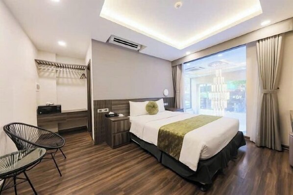 A modern hotel room with a large bed, a desk, a chair, and a window with curtains. - 3T Hotel Hanoi (Hanoi)