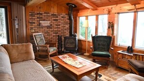 Ein gemütliches Blockhaus-Interieur mit Kamin, Holzmöbeln und großen Fenstern.