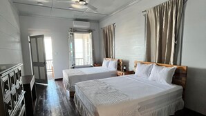 A hotel room with two beds, a ceiling fan, a wooden dresser, and a window with curtains. - The Ambassador's Terrace (Belize City)