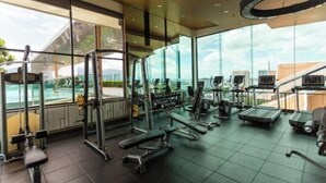 Una palestra moderna con diverse attrezzature per l'allenamento, ampie finestre e vista sull'esterno.