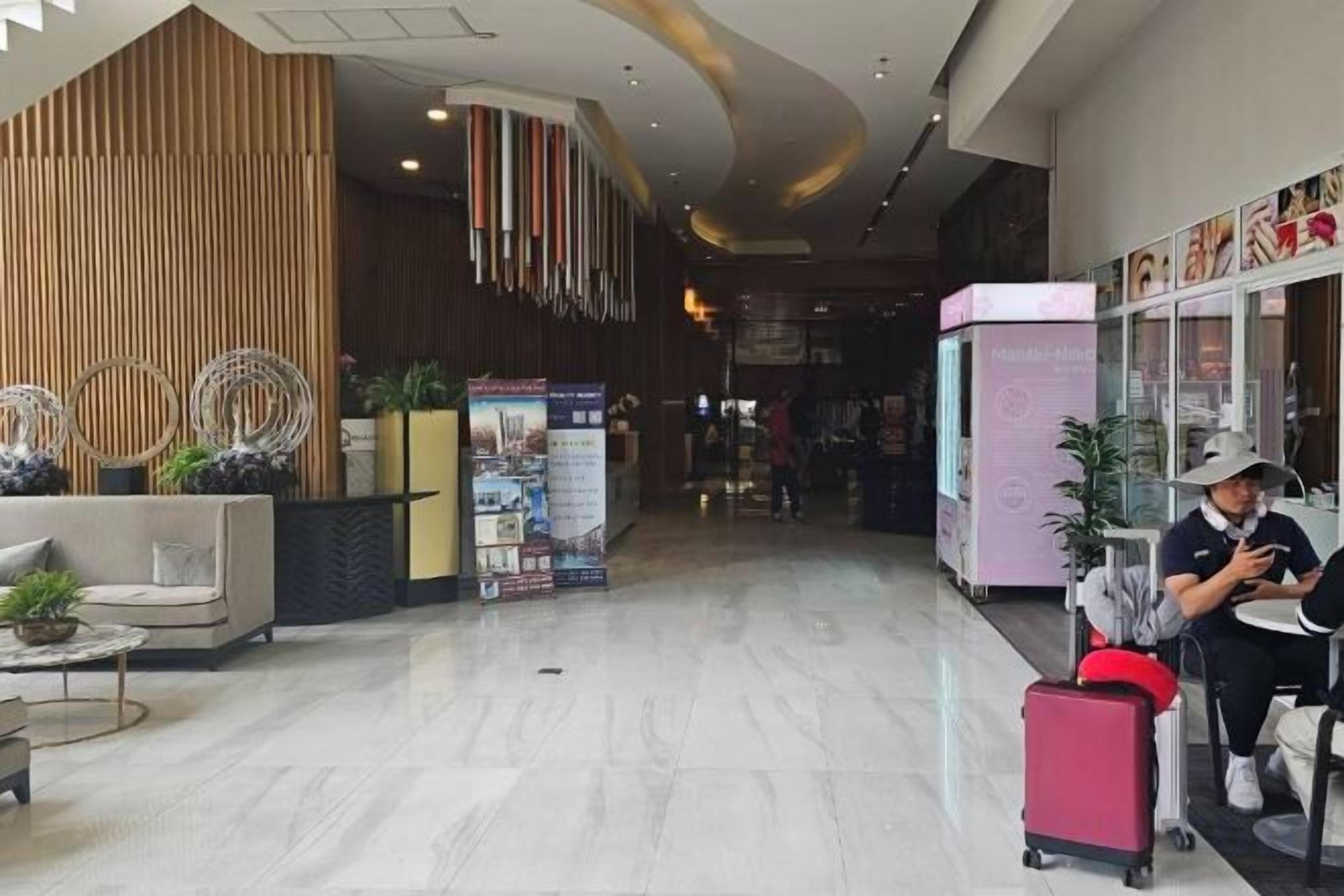 Un hall d’hôtel avec un comptoir d’accueil, un espace salon et une personne utilisant un appareil mobile.