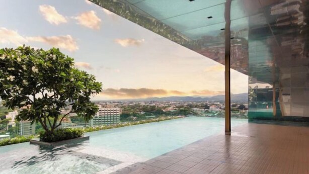 Una piscina a sfioro sul tetto con vista panoramica sulla città e montagne sullo sfondo.