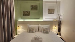 Un letto ben rifatto con due cuscini, un asciugamano piegato e due opere d'arte appese al muro.