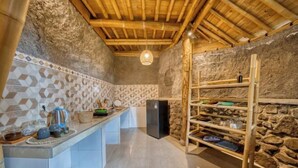 Eine rustikale Küche mit einer Steinwand, Holzbalken an der Decke und einer eingebauten Regaleinheit.
