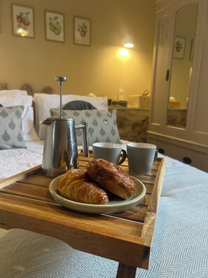 A tray with croissants, a coffee pot, and a cup on a wooden table in a hotel room. - A cosy countryside gite with pool, surrounded by nature and near the Pyrenees. (Laroque-d'Olmes)