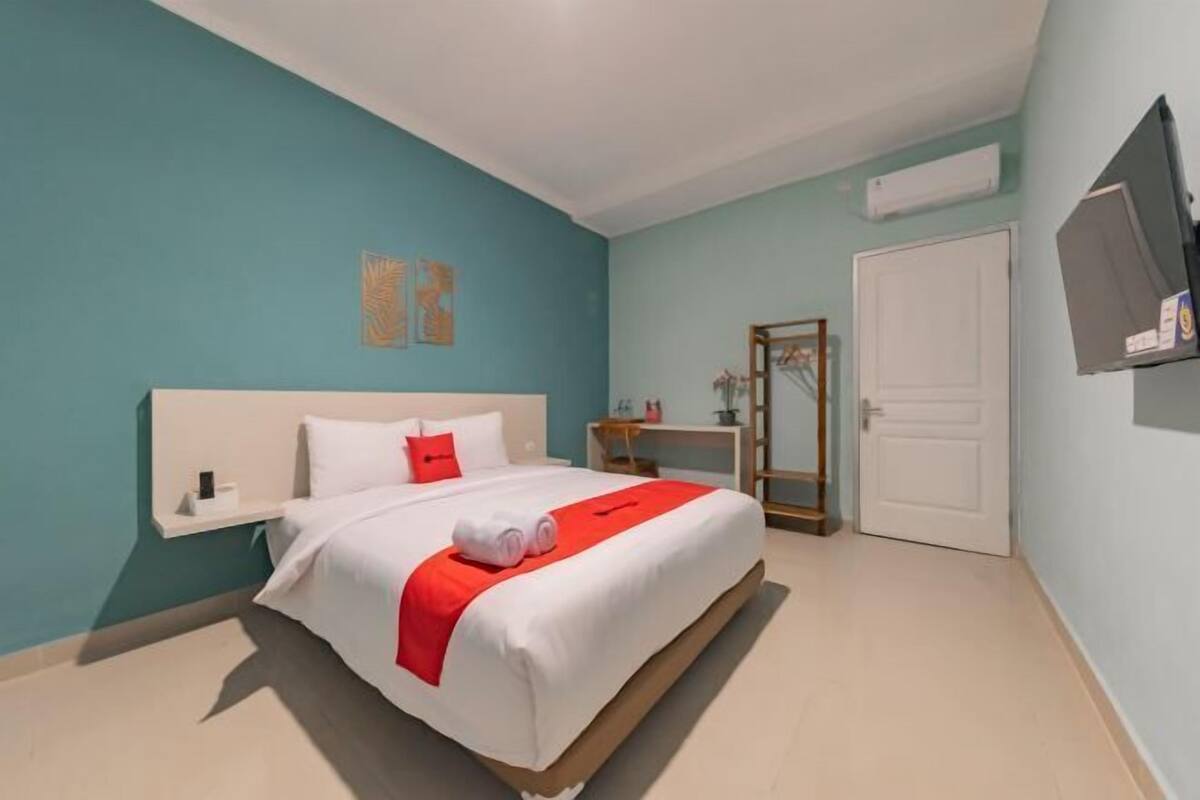 Un dormitorio con cama, mesita de noche, espejo y puerta.