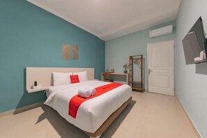 A bedroom with a bed, a bedside table, a mirror, and a door.