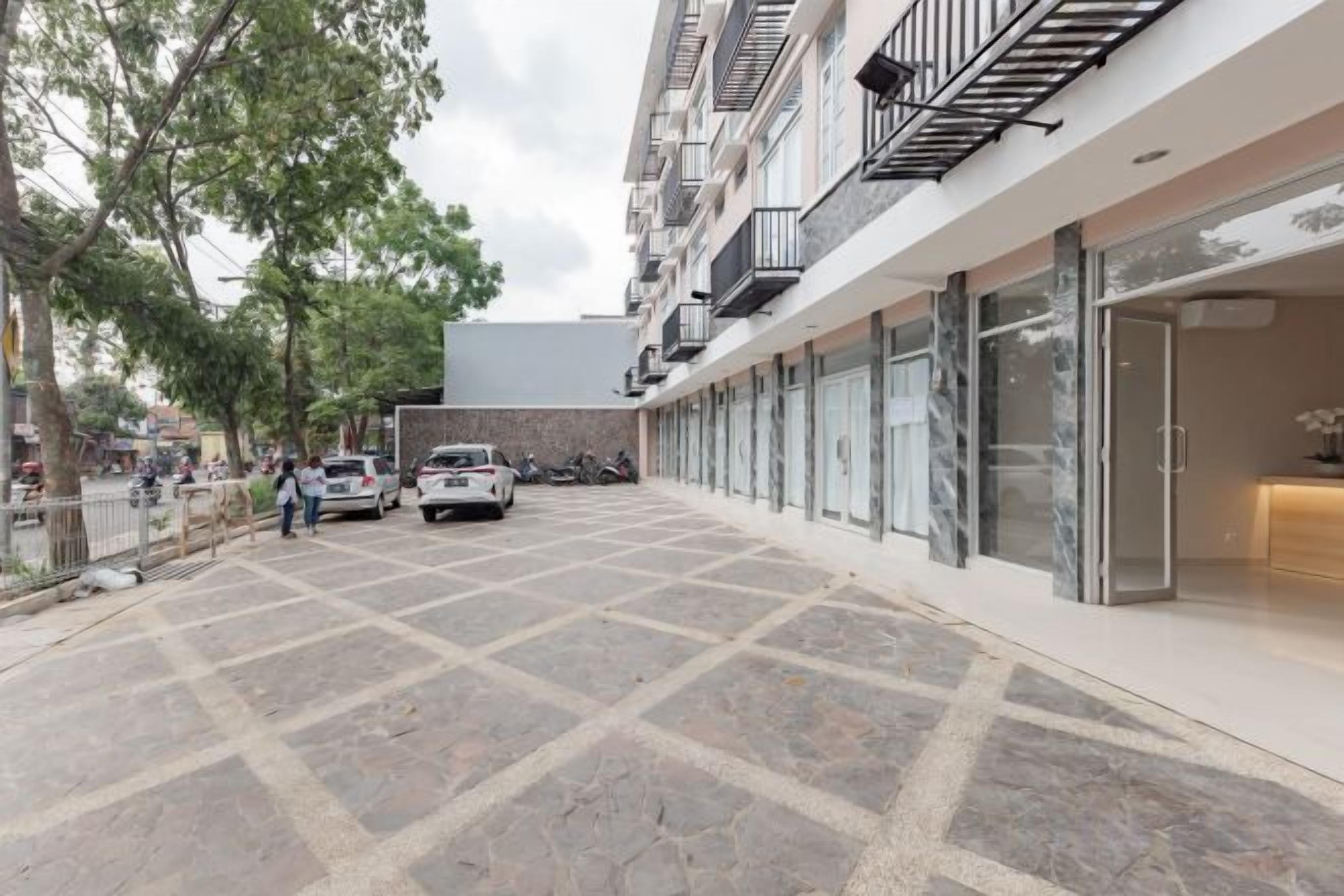 A building with a covered parking area, storefronts, and a gated entrance.