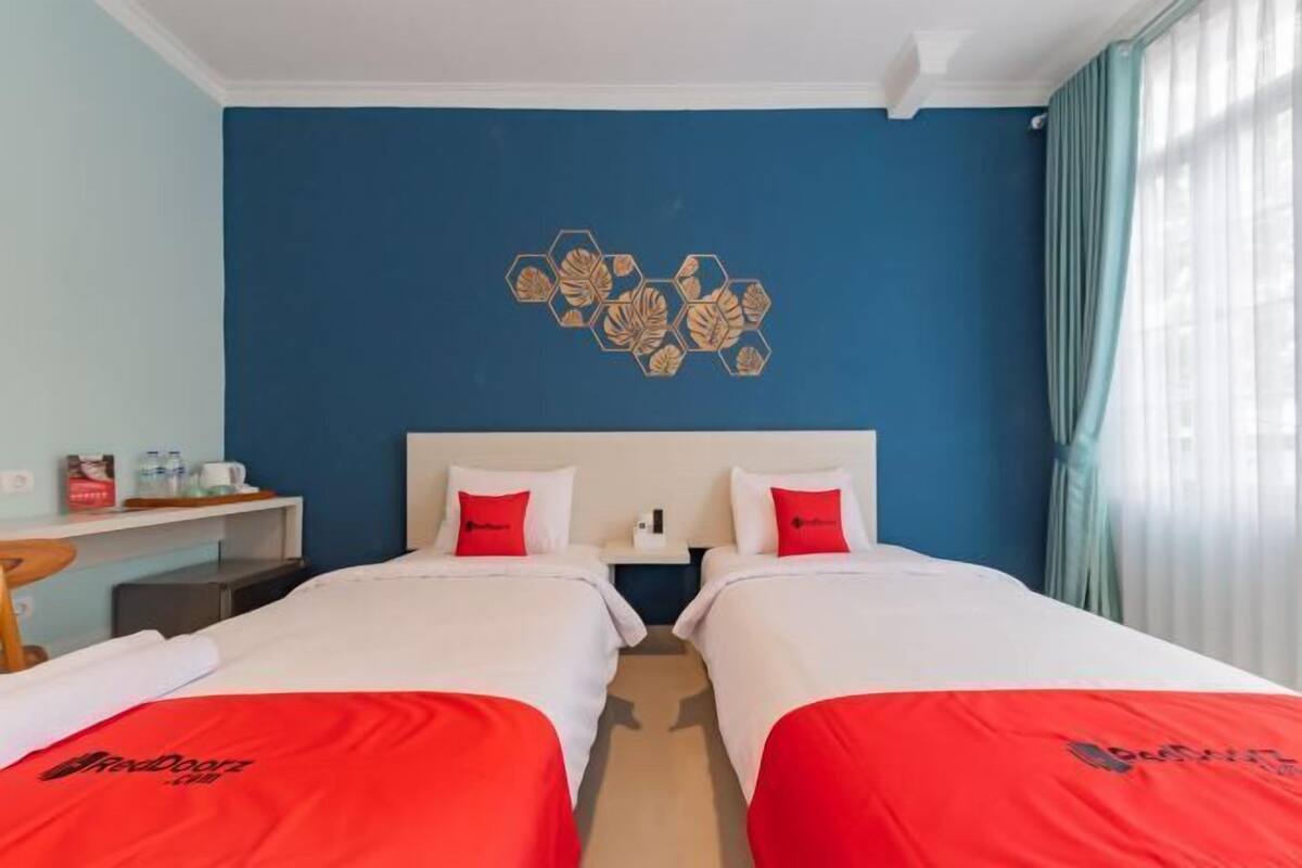 Habitación de hotel con dos camas, un muro azul decorativo y un motivo hexagonal.