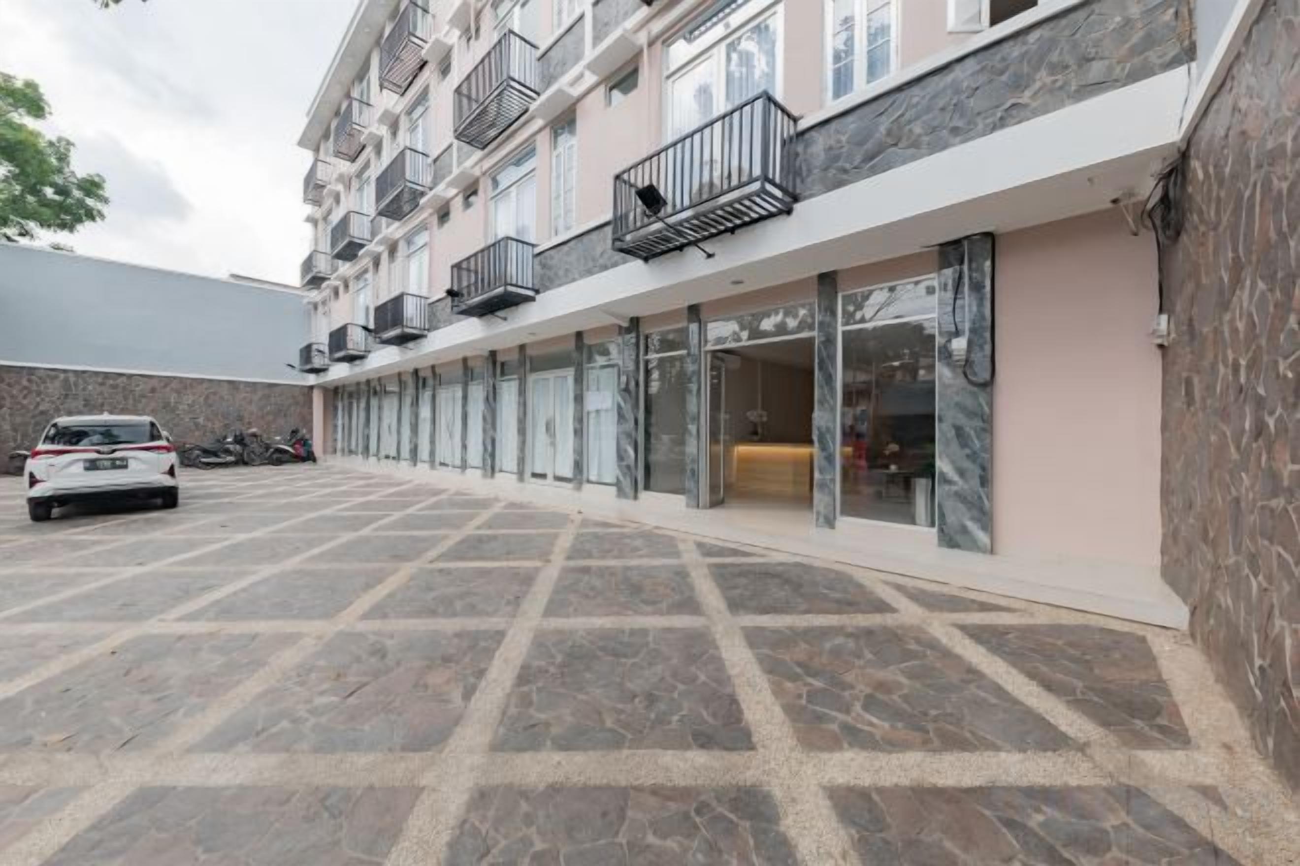 Un edificio de varios pisos con estacionamiento, balcones y una fachada comercial.