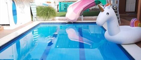 Une piscine avec un toboggan et un flotteur en forme de cygne.