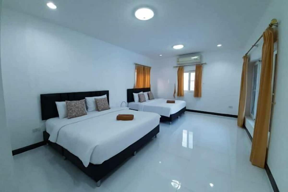 A hotel room with two beds, white bedding, and a large window with curtains.