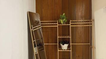 A wooden shelving unit with plants and a mirror.