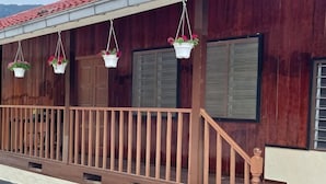 A wooden building with a balcony, hanging flower baskets, and a staircase. - Manson Goat Cottage (A) - Nature escape hideaway (Ulu Telom)