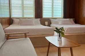 A hotel room with two beds, a wooden table, and a vase with a plant. - Manson Goat Cottage (A) - Nature escape hideaway (Ulu Telom)