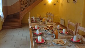 Ein Essbereich mit einem Holztisch, der für eine Mahlzeit gedeckt ist, einer Treppe und gelben Wänden.