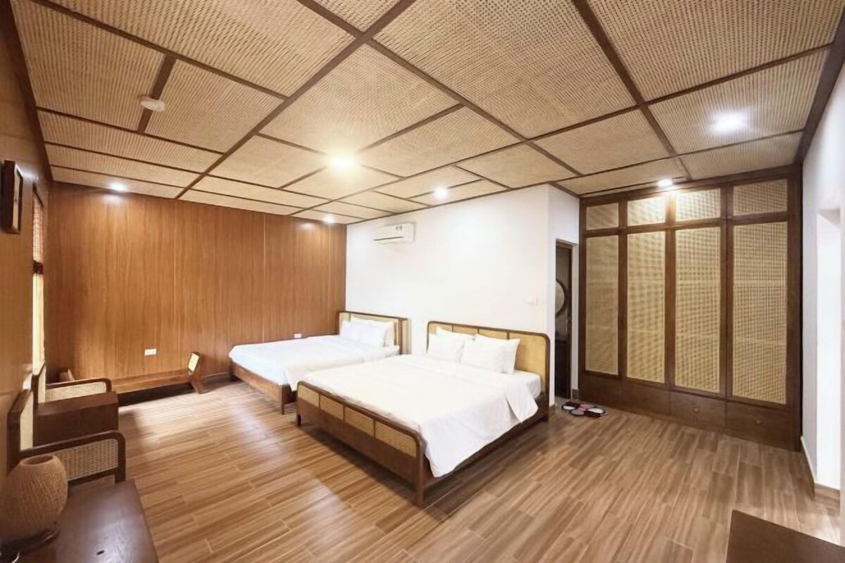 Een kamer met twee bedden, een houten vloer, een plafond met ruitmotief en een groot raam met uitzicht.