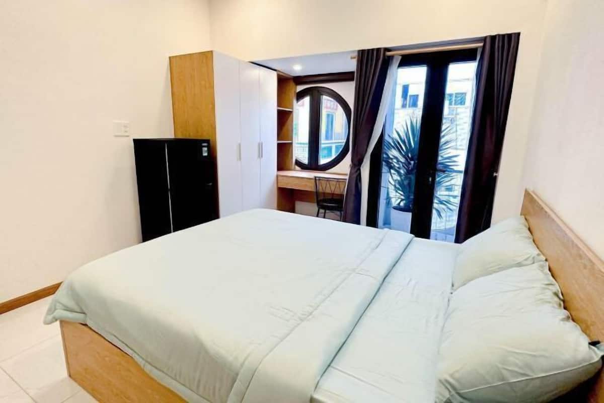 Une chambre à coucher avec un lit, une armoire, un bureau et une fenêtre avec des rideaux.