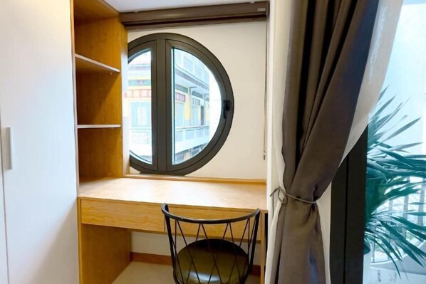 Une pièce avec un bureau en bois, une fenêtre ronde et une chaise.