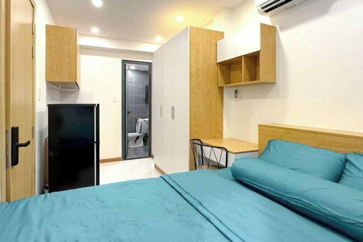 Une chambre à coucher de taille réduite, comprenant un lit, un bureau et une armoire.