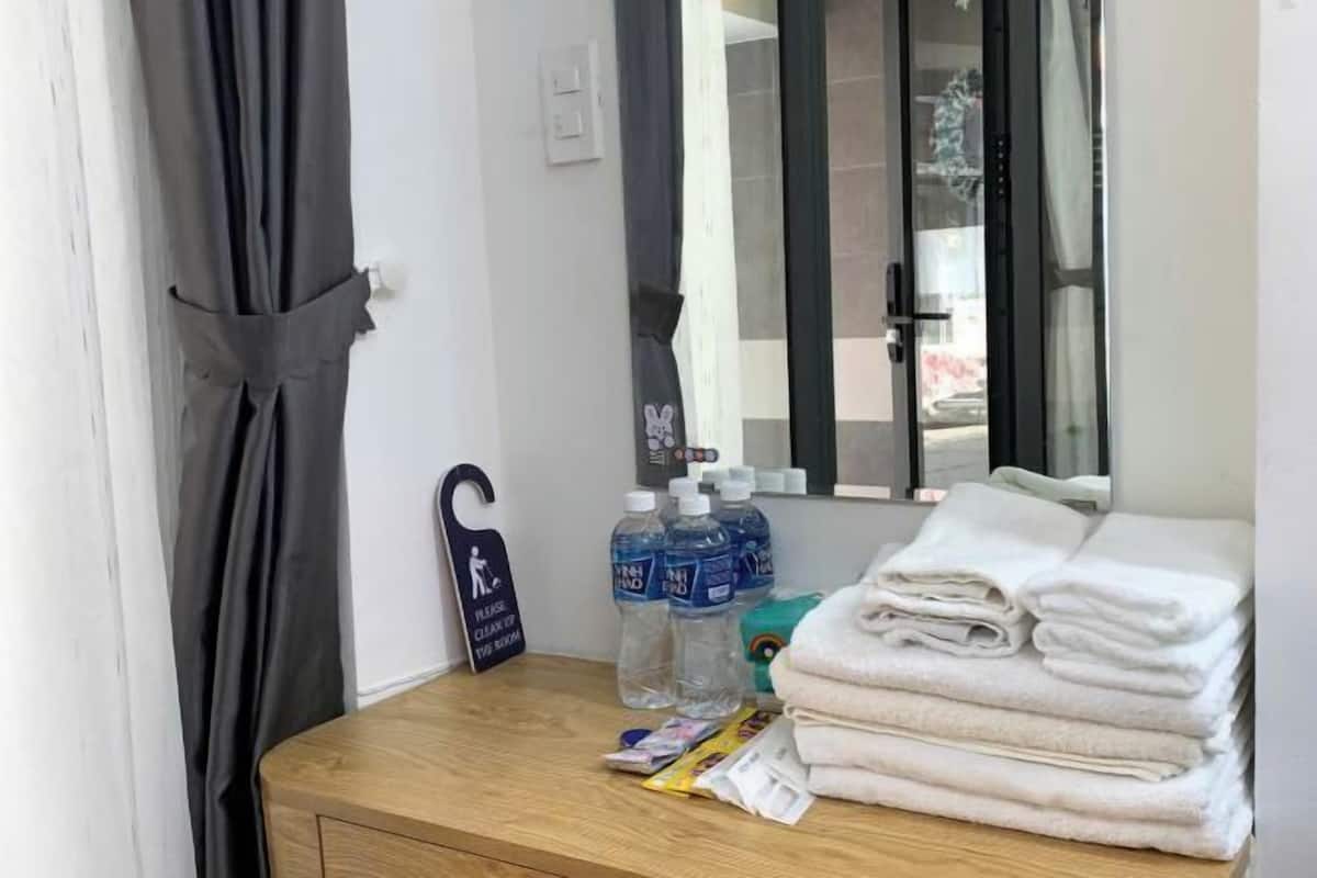 Une chambre d’hôtel avec un bureau en bois, un miroir, un panneau indiquant que la chambre est propre, et une pile de serviettes.