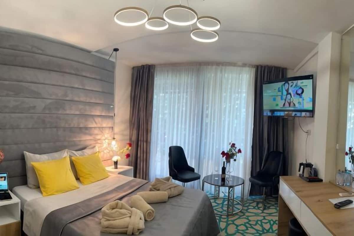 A hotel room with a bed, a desk, a TV, and a chair.