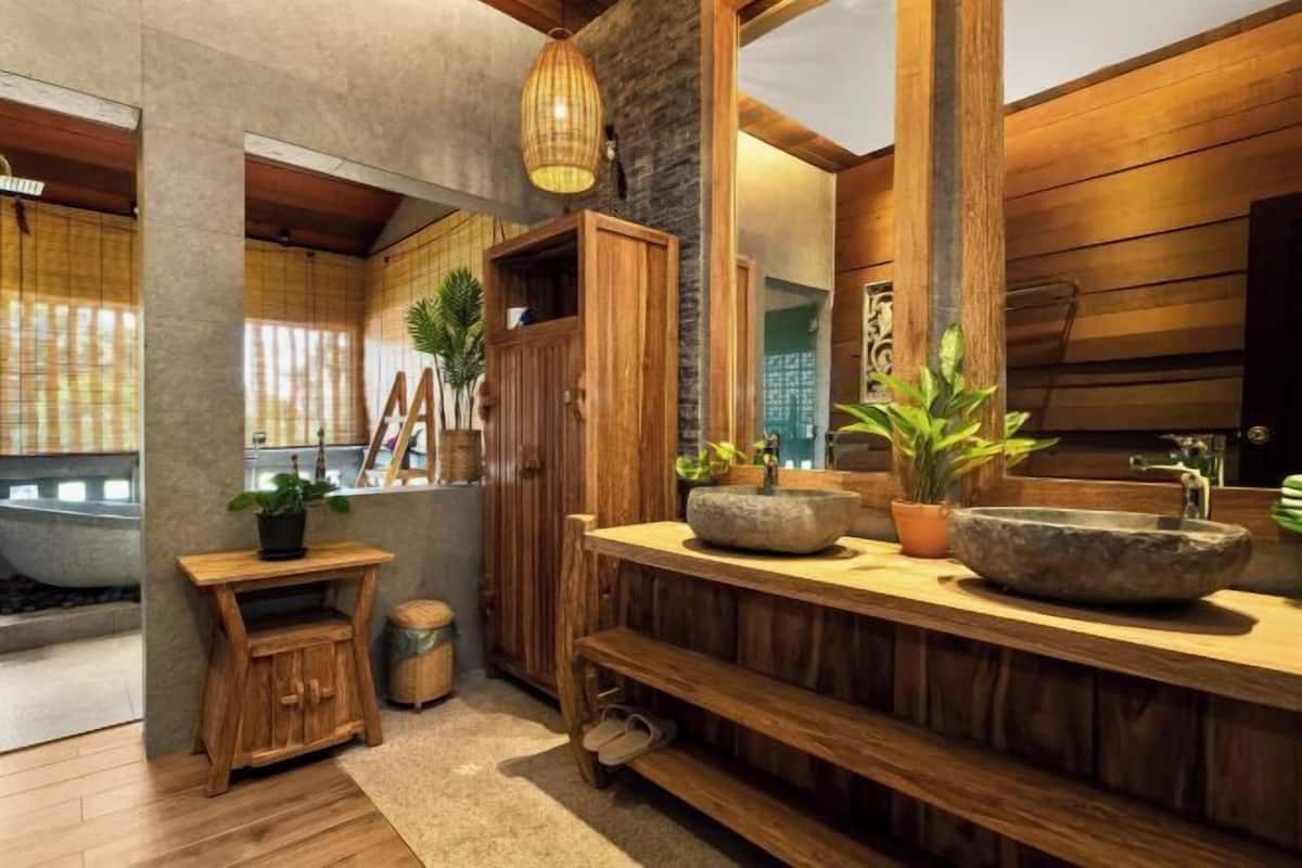 A bathroom with wooden cabinetry, a stone sink, and a mirror.