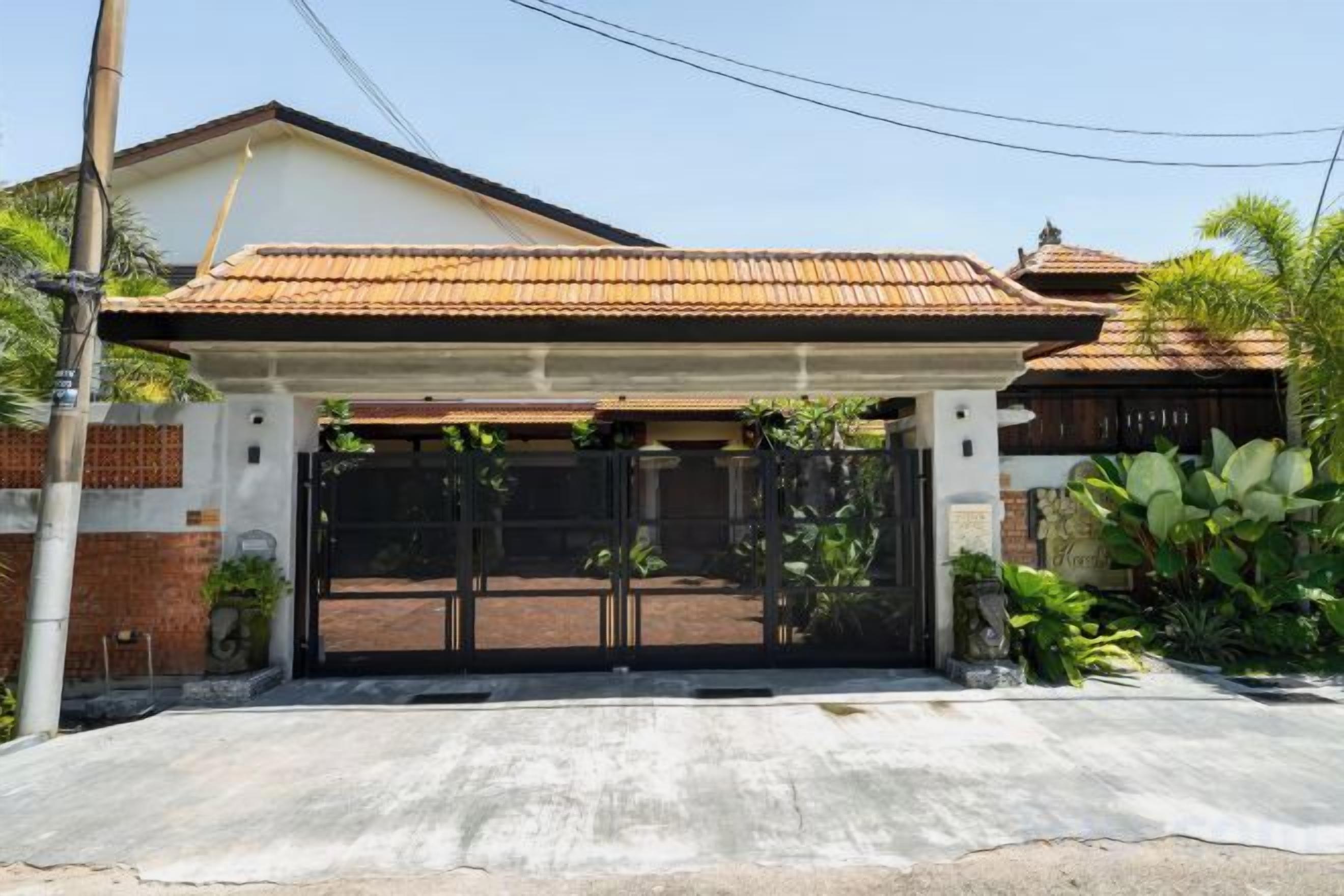 A residential property with a gated entrance, a covered porch, and a concrete driveway.
