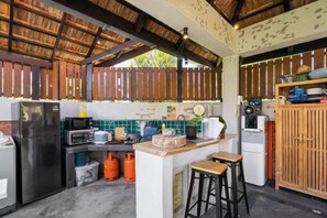 Cocina compacta equipada con refrigerador, microondas y estufa a gas. Hay taburetes y una pequeña barra.