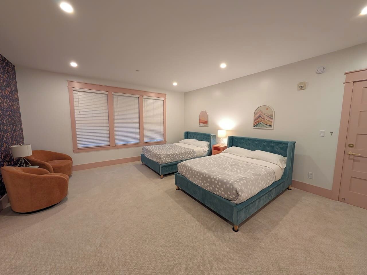 A bedroom with two beds, a chair, and a lamp.